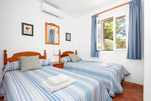 two beds in a room with a window at Villa María in Son Bou