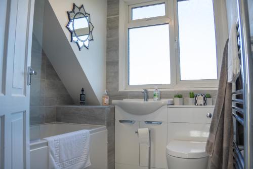 La salle de bains est pourvue d'un lavabo, de toilettes et d'une fenêtre. dans l'établissement Well-furnished 3-Bedroom house with Free Parking and Sky TV in Milton Keynes by HP Accommodation, à Milton Keynes