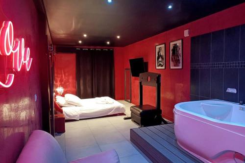 a red bathroom with a tub and a bed at Appartement balnéo et sauna privés The Red Room in Mauguio