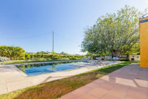 a swimming pool in a yard with chairs and trees at Masia Cal Sisplau, con piscina y rodeada de viñedos a 10 minutos de Vilafranca del Penedés, Barcelona ,Cataluña in San Martín Sarroca