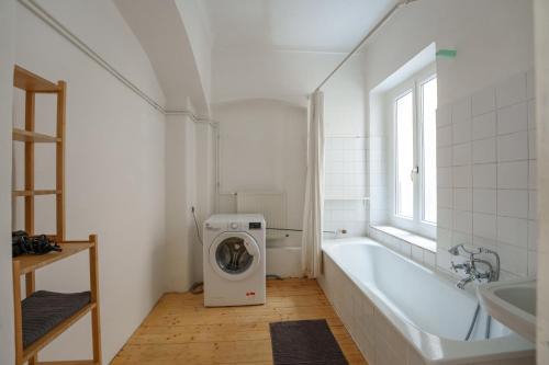 y baño blanco con lavadora y bañera. en Vienna Living Apartments - Barnabitengasse, en Viena