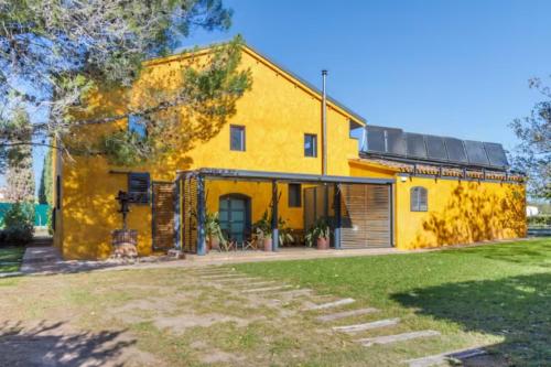 a yellow house with a garage at Masia Cal Sisplau, con piscina y rodeada de viñedos a 10 minutos de Vilafranca del Penedés, Barcelona ,Cataluña in San Martín Sarroca
