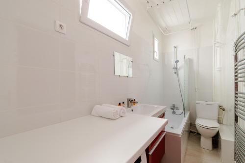 une salle de bain blanche avec un lavabo et des toilettes dans l'établissement Veeve - Swan's Nest, à Paris
