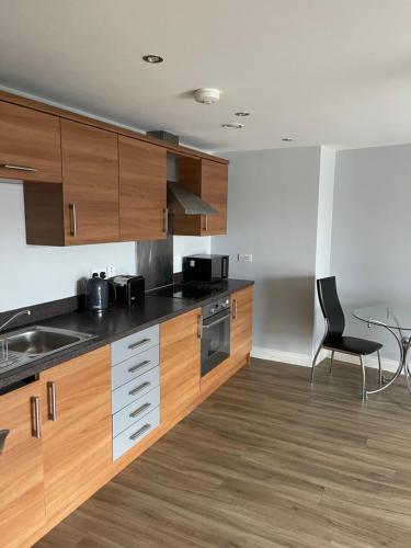 a kitchen with wooden cabinets and a black chair at Belgrade Plaza Serviced Apartments in Coventry
