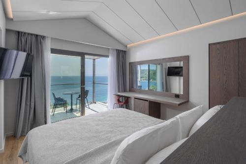 a bedroom with a bed and a view of the ocean at Adrina Grand Hotel in Panormos Skopelos