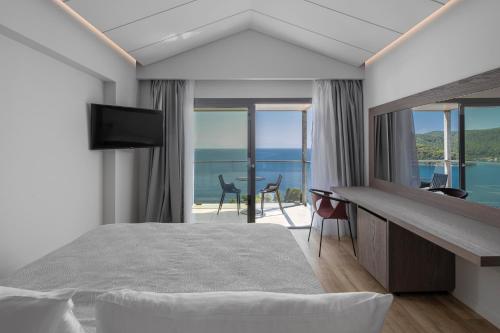 a bedroom with a bed and a view of the ocean at Adrina Grand Hotel in Panormos Skopelos