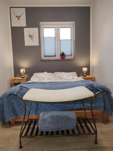 a bed with a blue blanket and two windows at Apartamenty & Pokoje pod Gruszą in Kudowa-Zdrój