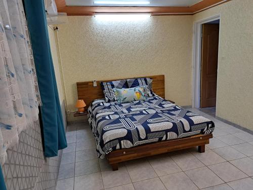 a bedroom with a bed with a blue and white comforter at Maison meublée F2 avec vue et piscine in Ravine des Cabris