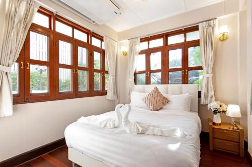 a bedroom with a white bed with windows at Sathorn Private Pool Villa in Bangkok