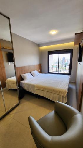 1 dormitorio con cama, silla y espejo en Lar no Bueno en Goiânia