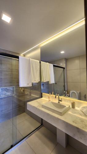 uma casa de banho com um lavatório, um chuveiro e um espelho. em Lar no Bueno em Goiânia
