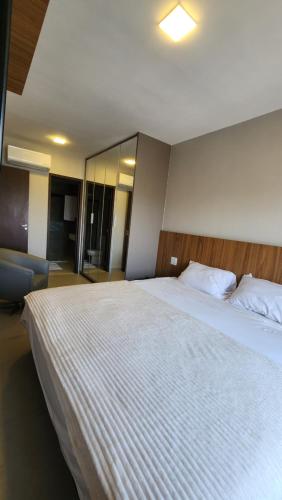 a bedroom with a large white bed with a mirror at Lar no Bueno in Goiânia