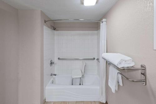 uma casa de banho com um chuveiro e uma banheira branca em Days Inn by Wyndham Oklahoma City em Oklahoma City