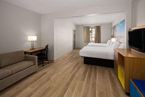 a hotel room with a bed and a couch and a tv at Days Inn by Wyndham Oklahoma City in Oklahoma City