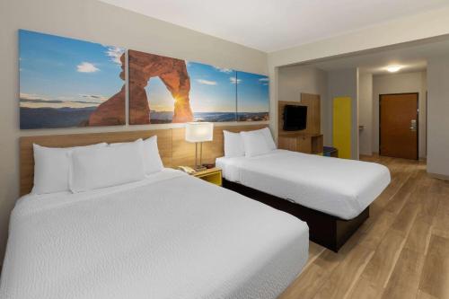 a hotel room with two beds and a painting on the wall at Days Inn by Wyndham Oklahoma City in Oklahoma City