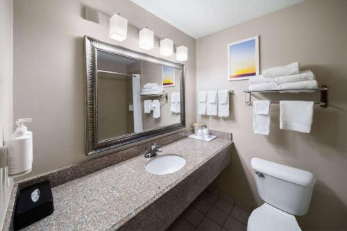 a bathroom with a sink and a toilet and a mirror at Days Inn by Wyndham Oklahoma City in Oklahoma City