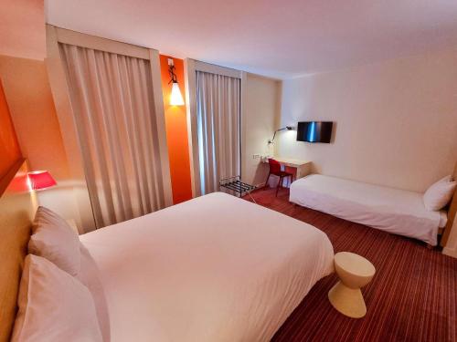 una camera d'albergo con 2 letti e una scrivania di ibis Styles Le Puy en Velay a Le Puy en Velay