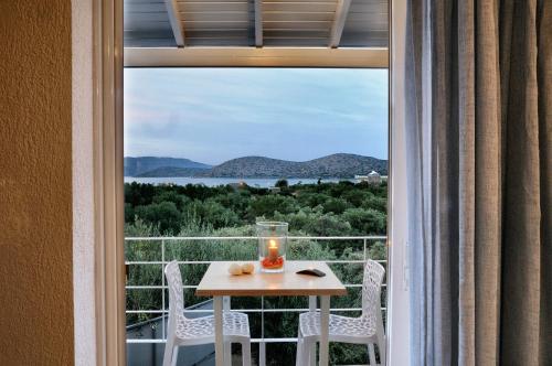 a window with a table and chairs and a candle at Elounda Krini Hotel in Elounda
