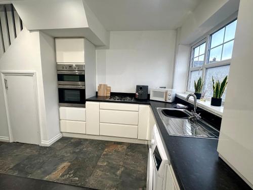 a kitchen with white cabinets and a black counter top at Seaton House by Blue Skies Stays in Seaton Carew