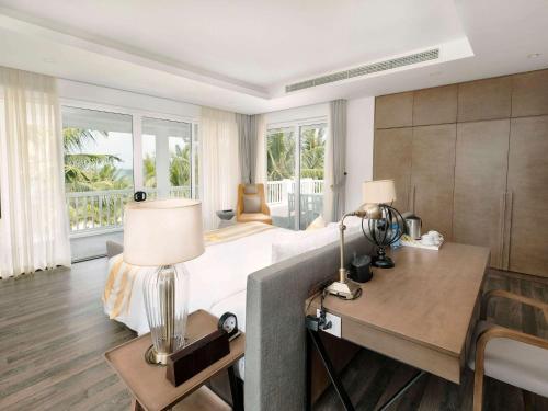 1 dormitorio con 1 cama y escritorio con lámpara en Premier Village Danang Resort Managed By Accor, en Da Nang