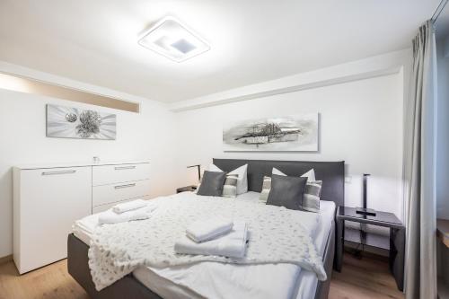 a white bedroom with a bed with towels on it at Oma's Küche & Quartier in Binz