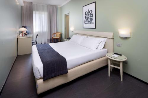ミラノにあるベストウエスタン ホテル メジャーの大きなベッドとテーブルが備わるホテルルームです。