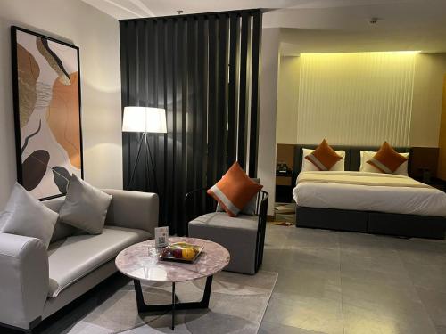 um quarto de hotel com uma cama, um sofá e uma mesa em Al Muhaidb Residence Jawazat em Riade