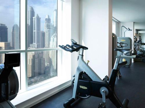 a gym with a view of a city from a window at Pullman Dubai Jumeirah Lakes Towers in Dubai