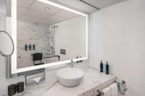 Baño blanco con espejo grande y lavabo en Hilton Vienna Waterfront, en Viena