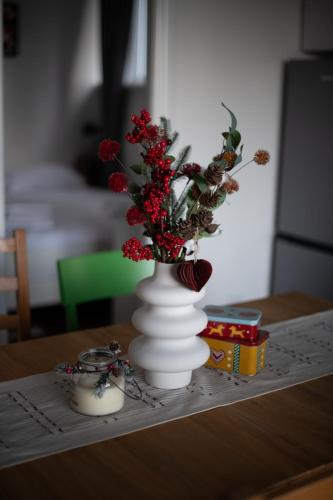 a white vase with red flowers in it on a table at Kuca 59 in Jahorina