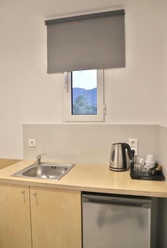 a kitchen counter with a sink and a window at Elounda Krini Hotel in Elounda
