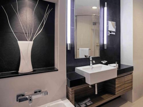 a bathroom with a sink and a vase on the wall at Pullman Dubai Jumeirah Lakes Towers in Dubai