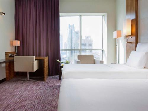 a hotel room with two beds and a large window at Pullman Dubai Jumeirah Lakes Towers in Dubai