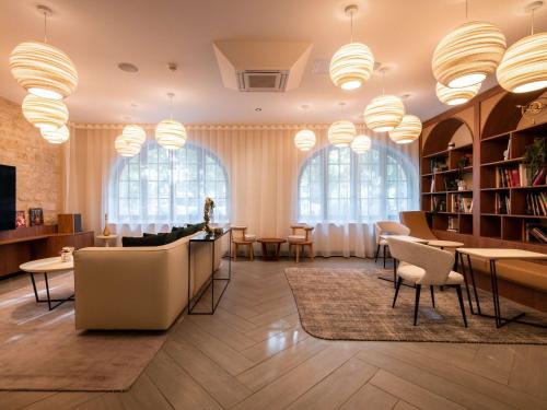 een bibliotheek met stoelen en tafels en grote ramen bij Mercure Paris Ouest Saint Germain in Saint-Germain-en-Laye