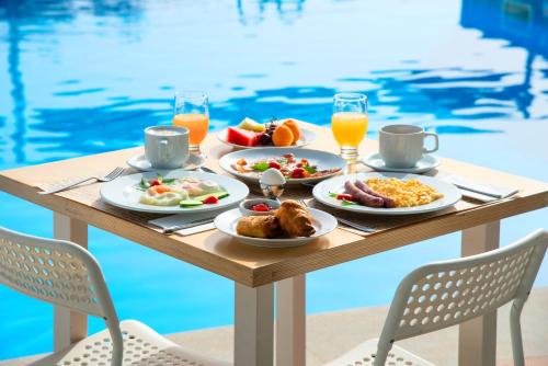 a table with breakfast food on it next to a pool at Elounda Krini Hotel in Elounda