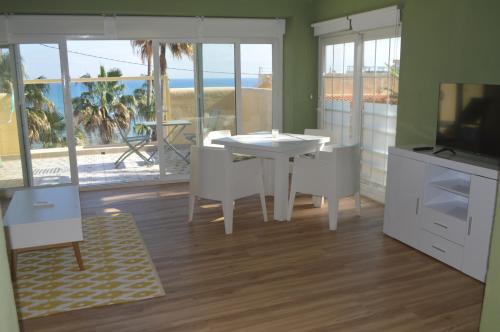 a living room with a white table and a television at Extraordinario apartamento a pie de playa en Chalet Roquetes in Alicante