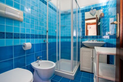 a blue tiled bathroom with a toilet and a sink at Galathee Sea View in Puntaldia