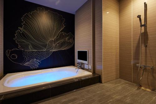 a bathroom with a bath tub and a tv at ホテル 尼乃美楽 尼崎 in Amagasaki