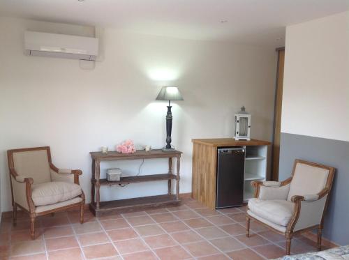 a room with two chairs and a table and a refrigerator at Le Patio Fleuri in Lorgues