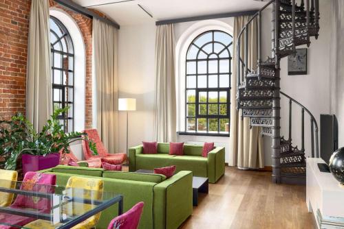 a living room with green couches and windows at Vienna House by Wyndham Andel's Lodz in Łódź