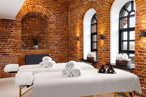 two beds in a room with a brick wall at Vienna House by Wyndham Andel's Lodz in Łódź