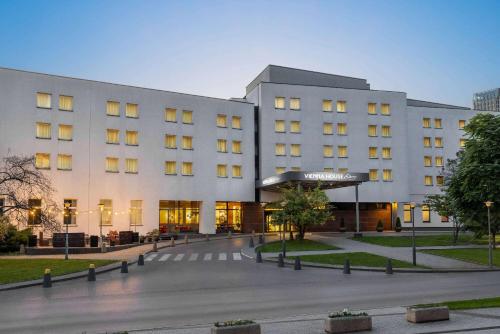 a large white building with a courtyard in front of it at Vienna House Easy by Wyndham Cracow in Kraków