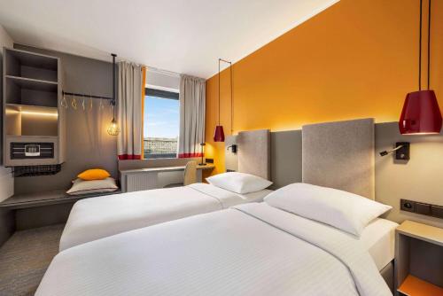 a hotel room with two beds and a kitchen at Vienna House Easy by Wyndham Cracow in Krakow