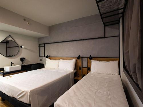 a bedroom with two beds and a mirror at ibis Barra do Garcas in Barra do Garças