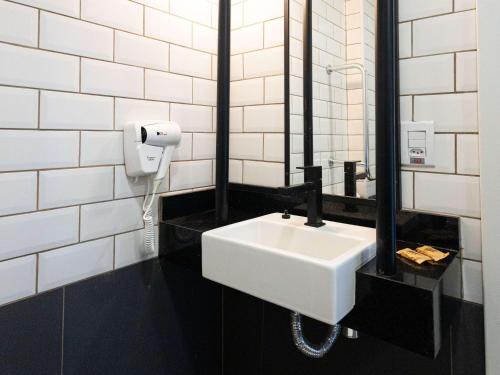 uma casa de banho com um lavatório branco e um espelho. em ibis Barra do Garcas em Barra do Garças