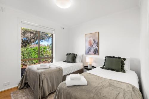 a white room with two beds and a window at Wilson Executive Apartments in Thomson