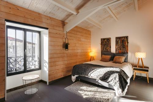 Schlafzimmer mit Holzwänden, einem Bett und einem Fenster in der Unterkunft Villa la forge expérience bien-être in Nuaillé-dʼAunis