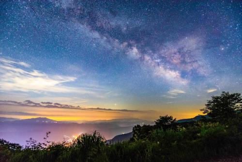 a starry sky with a milky way over a mountain at FLYING HOUSE in Chikuni