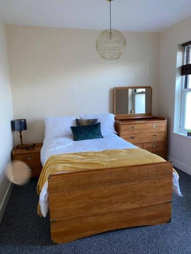 a bedroom with a bed with a dresser and a mirror at Dorset Lodge Flat 3 in Gloucestershire
