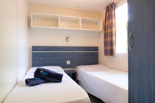 una habitación con 2 camas y una bolsa encima en Happy Camp Mobile Homes in Camping Karavomilos Beach, en Sami